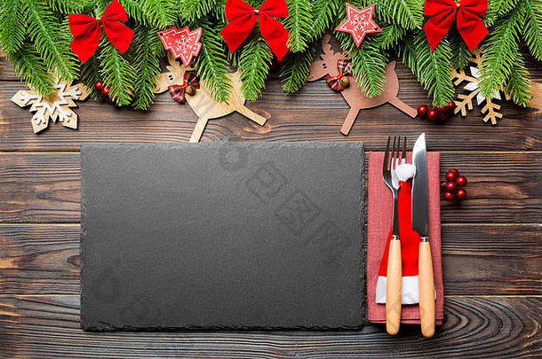 木制背景上的圣诞晚餐俯视图。盘子、器皿、枞树和节日装饰品，带有空间。新年时间概念。