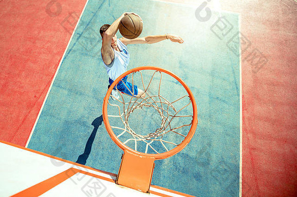 年轻人在街球、篮球上跳跃并完成了一个精彩的扣篮。城市真实。