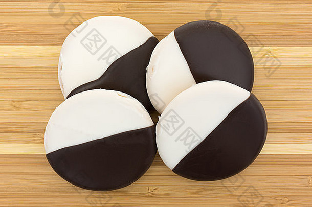 四块蛋糕饼干的俯视图，香草和巧克力糖衣放在木砧板上。