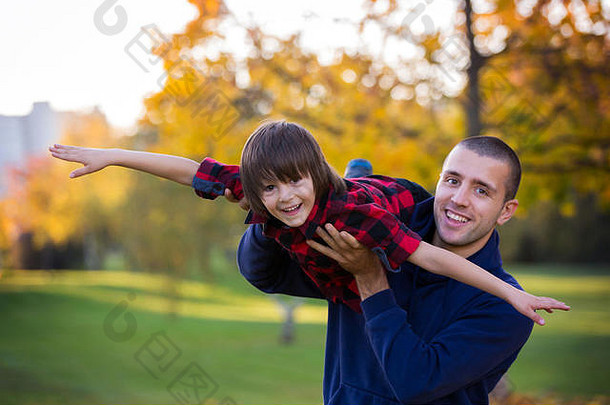 快乐的年轻人和孩子在公园的户外玩耍。秋日公园父子嬉戏的家庭生活场景