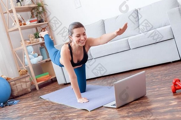 健康的生活方式。年轻女子在家做瑜伽手和膝盖平衡姿势在笔记本电脑上看指<strong>导视</strong>频