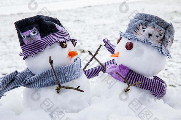 两个可爱的雪人穿着围巾和帽子过冬，彼此拥抱，成为<strong>久违</strong>的朋友。冬天的雪景。