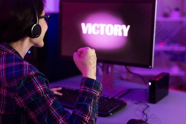 赢得电脑游戏的玩家女孩坐在电脑前室内，后视图