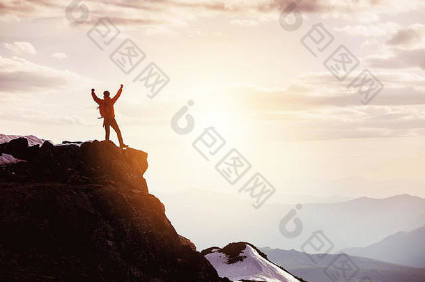 男子在山顶对着群山和日落摆出胜利者的姿势