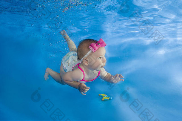 一个穿着连衣裙的小女孩漂浮在水池里的水下