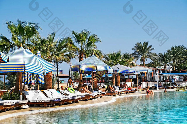 人放松池太阳便鞋阳伞棕榈树度假胜地埃及沙姆谢赫。9月