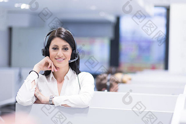 年轻微笑的呼叫中心女接线员戴着耳机工作