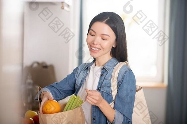 一个漂亮的年轻女子，手里拿着一袋蔬菜和水果。