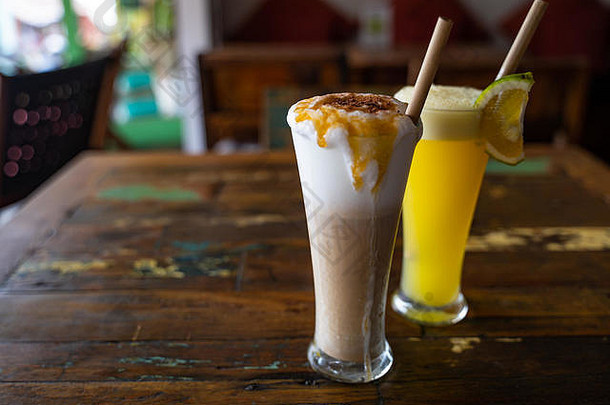 咖啡馆的木制古董桌上，高高的玻璃杯里放着鲜榨橙汁和巧克力奶昔，上面放着吸管。拷贝空间