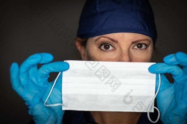 女医生或护士戴着外科手套，手持医用口罩。