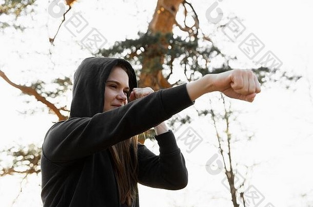 年轻的女运动员在公园里打拳击。年轻女子正在训练一个直击，重点放在眼睛上