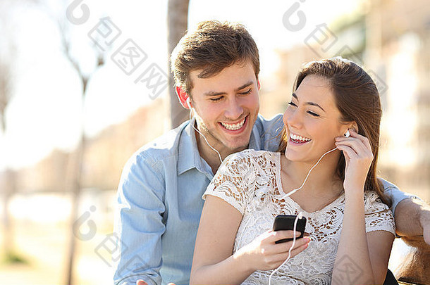 夫妇听音乐耳塞聪明的电话公园城市背景