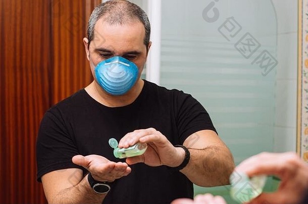 戴口罩的男子在手上涂抹消毒消毒剂以防止病毒病菌
