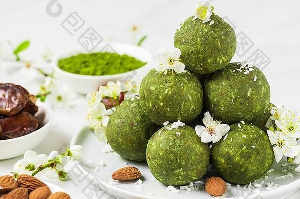 自制的生能源球使绿色火柴茶日期坚果春天花健康的素食主义者甜点食物白色背景食物样式