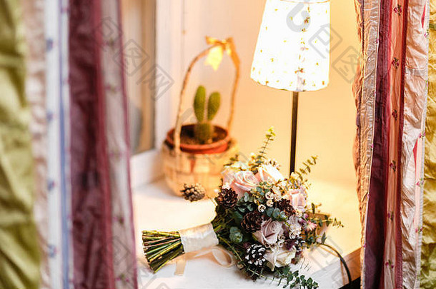 新婚新娘鲜花束。桌上摆着白色的毛茛花。温暖的夜晚气氛