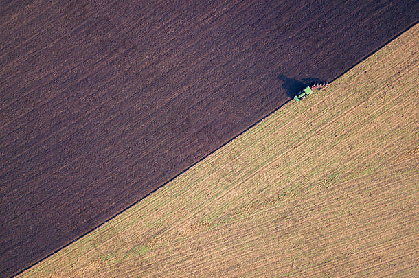 一辆拖拉机在农村犁地的航拍照片，乡村商业概念。秋天犁地，无人驾驶飞机射击。