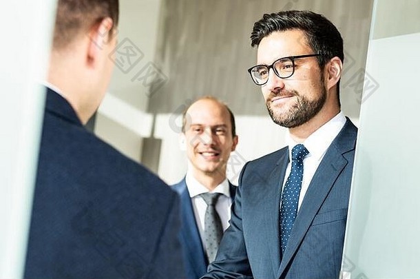 一群自信的商务人士在现代办公室的商务会议上握手致意，或通过握手结束交易协议。