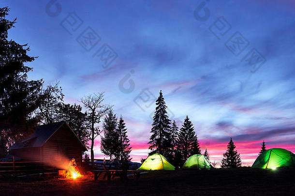 夜间露营。游客们在明亮的帐篷和木屋附近的篝火旁休息，在充满星星和银河的令人惊叹的夜空<strong>下</strong>