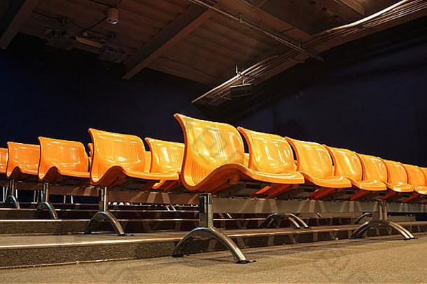 一个现代化的演讲厅，有一排排橙色塑料座椅