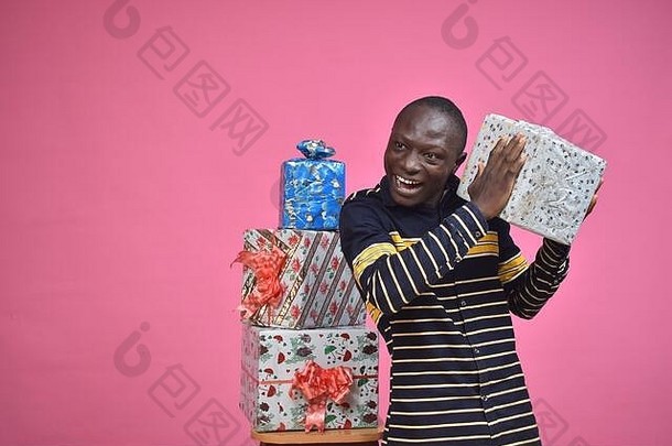 兴奋的年轻黑人拿着一个礼盒，站在一堆礼盒旁边，看他是否能确定礼物的内容