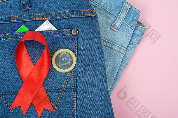 蓝色牛仔裤背景上的红丝带和避孕套。认识和保护艾滋病、艾滋病毒的概念。12月1日