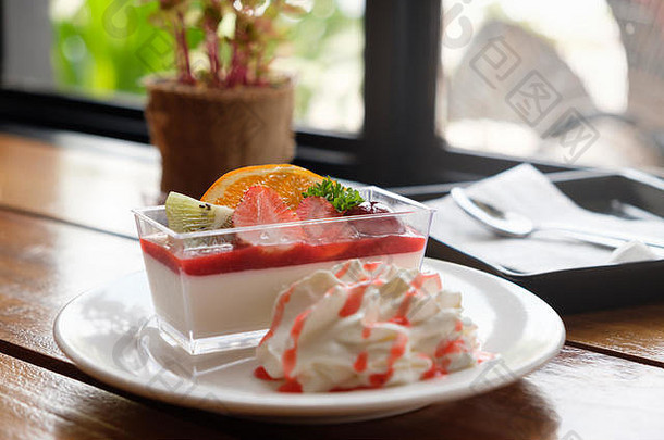 咖啡厅的什锦水果慕斯蛋糕，配以新鲜水果，如葡萄、橙子、猕猴桃和草莓。
