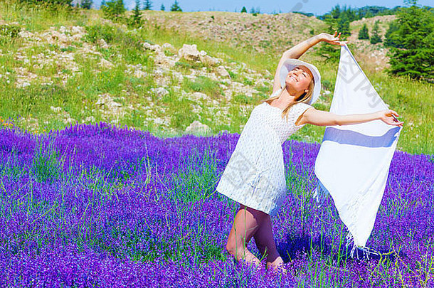 美丽的金发碧眼的女人持有手白色披肩跳舞紫色的薰衣草花场阳光明媚的一天夏天季节