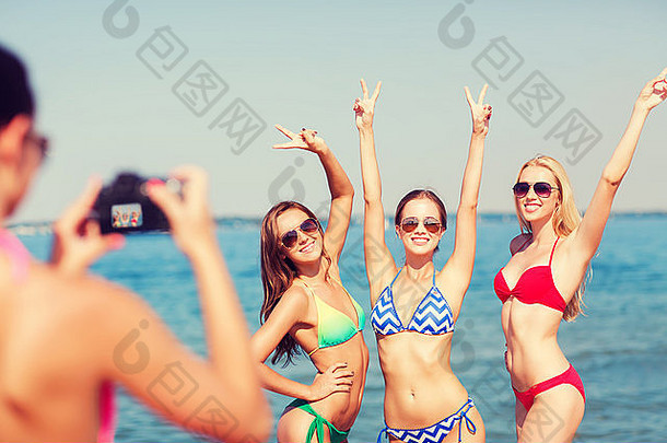 一群微笑的妇女在海滩上拍照