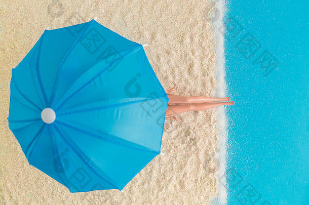洋娃娃腿放在沙滩上，在阳伞下享受暑假的极简创意理念。