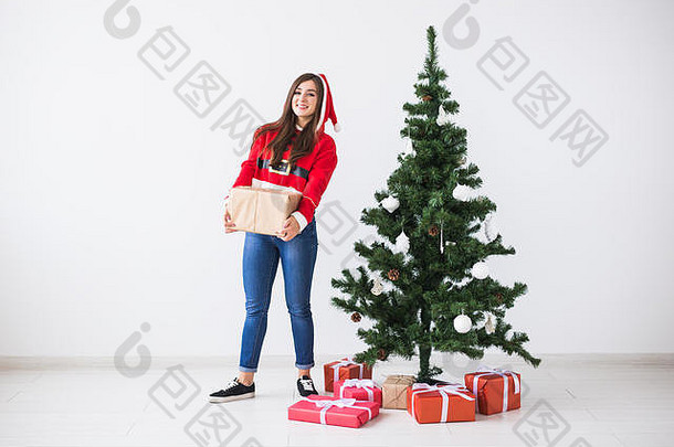 年轻的快乐的女人持有礼物盒子穿圣诞老人服装圣诞节树背景复制空间