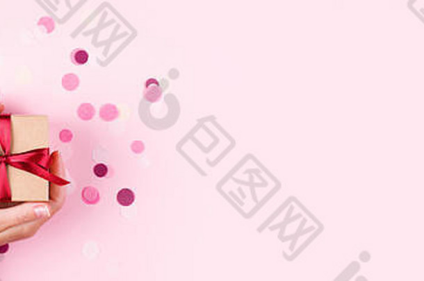 女人的手持有卡夫礼物盒子红色的弓粉红色的背景装饰五彩纸屑前视图假期现在概念复制空间横幅