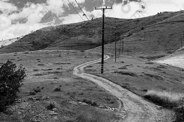 黑白相间，田野上有土路，电话线杆通向远处的小山。