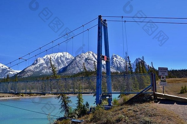 蓝松石河上的蓝色吊桥。高山积雪，蓝天，晴天。库特内平原生态保护区，加拿大。