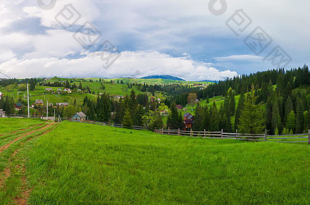风景如画的春天山场景木分裂铁路栅栏绿色郁郁葱葱的牧场国家路房子谷surrounde