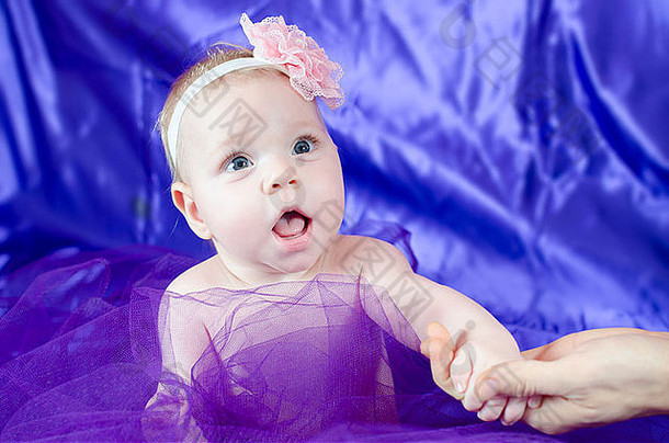 父持有婴儿女孩紫色缎背景