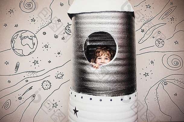 穿着宇航员服装玩手工火箭的快乐的孩子。
