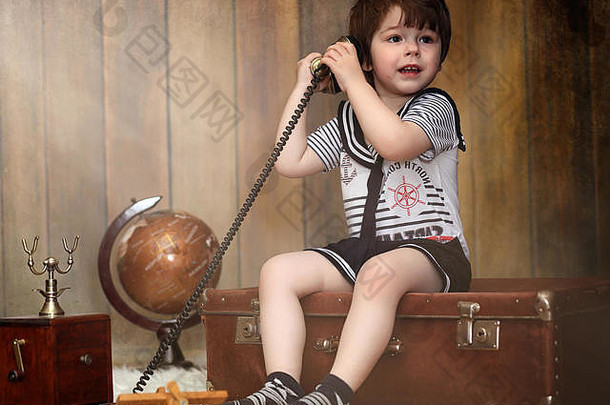 一个穿着复古内饰的孩子和一部旧手机坐在地板上。