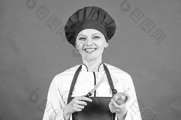烹饪戴厨师帽和围裙的女人。快乐女人用食谱烹饪健康食品。拿着烹饪刀和洋葱的家庭主妇。厨房里的专业厨师。我饿了。