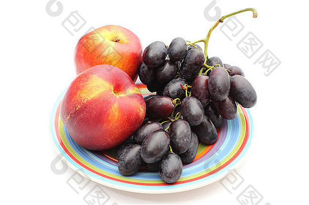 在白色背景上分离的色板上的葡萄和油桃