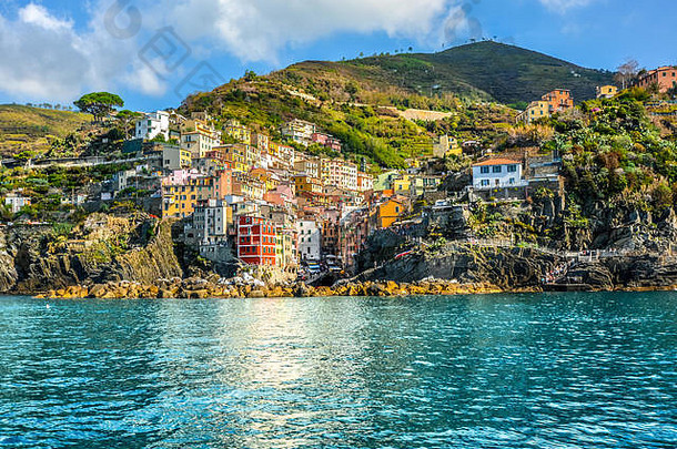 意大利Riomaggiore五彩缤纷的海滨和山坡村庄，初秋时位于Cinque Terre的利古里亚海岸，海水湛蓝。