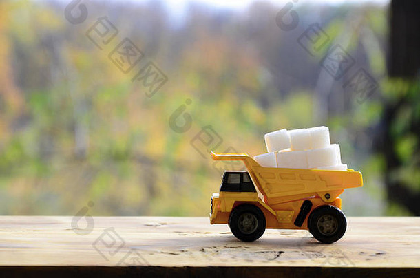 小黄色的玩具卡车加载白色糖多维数据集车木表面背景秋天森林提取运输
