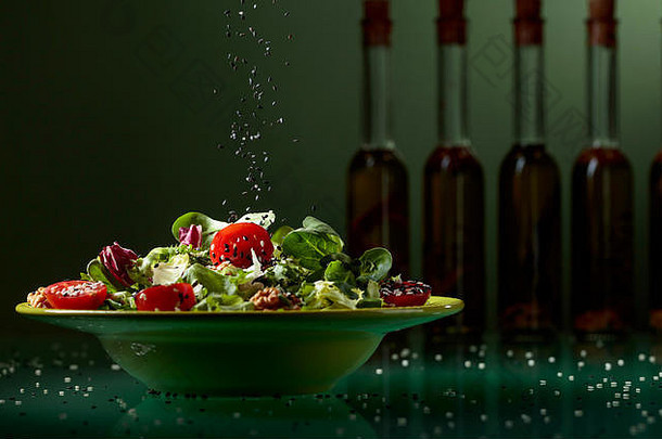 绿色沙拉樱桃西红柿核桃蔬菜石油撒上黑色的芝麻背景轮廓橄榄石油瓶