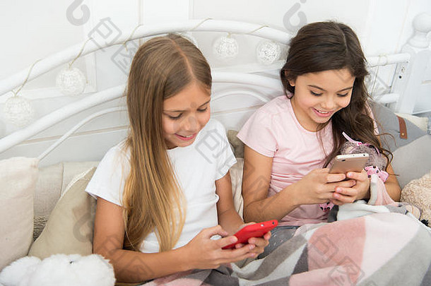 只是在屏幕上滑动手指。快乐的孩子们用手机。通过手机发<strong>送</strong>圣诞和<strong>新年</strong>祝福短信。小女孩在床上使用智能手机。圣诞快乐，<strong>新年</strong>快乐。