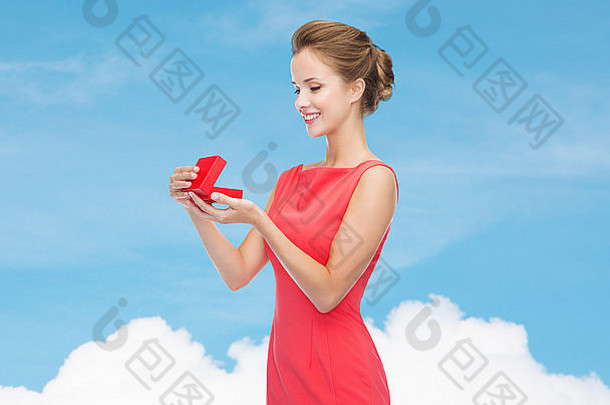 身着红色连衣裙，带着礼盒，面带微笑的年轻女子