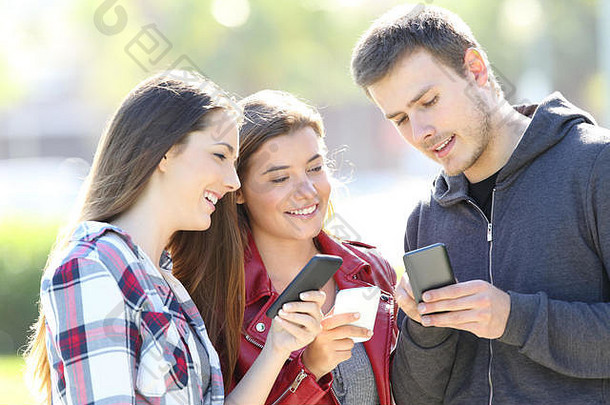 三个朋友在一起聊天，每个人都拿着智能手机站在街上