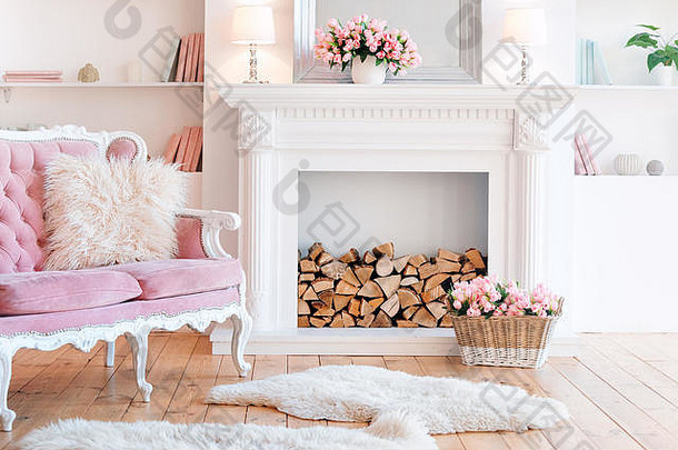 现代灯光内饰，带壁炉、春花和舒适的粉色沙发