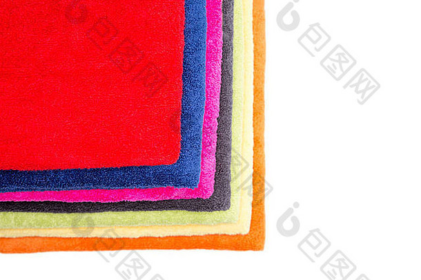五颜六色的蓬松干净的新鲜毛巾整齐地叠在一起，展示它们的颜色，上面有一条红色的，从远处看