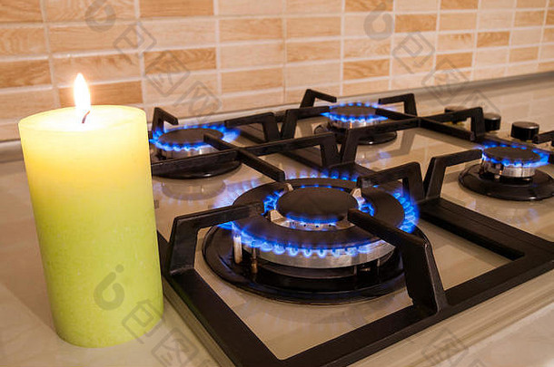家庭厨房炉子上蓝色火焰的特写镜头。燃气灶，火焰为丙烷气和蜡烛。新旧观念
