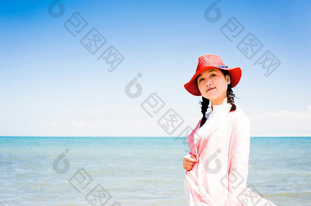 在海边戴着红帽子的亚洲女人，微笑着