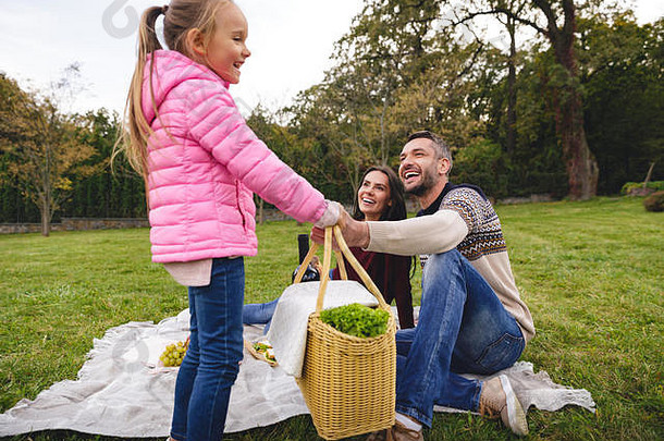快乐的小女孩在户外给她爸爸野餐篮